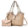 Beige crocodile-style handbag with gold-tone chain-link handles and shoulder strap, pictured beside a beige envelope pouch