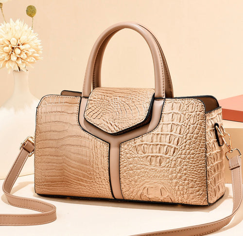 Beige crocodile-style textured satchel handbag with rounded twin handles, smooth beige trim, and shoulder strap